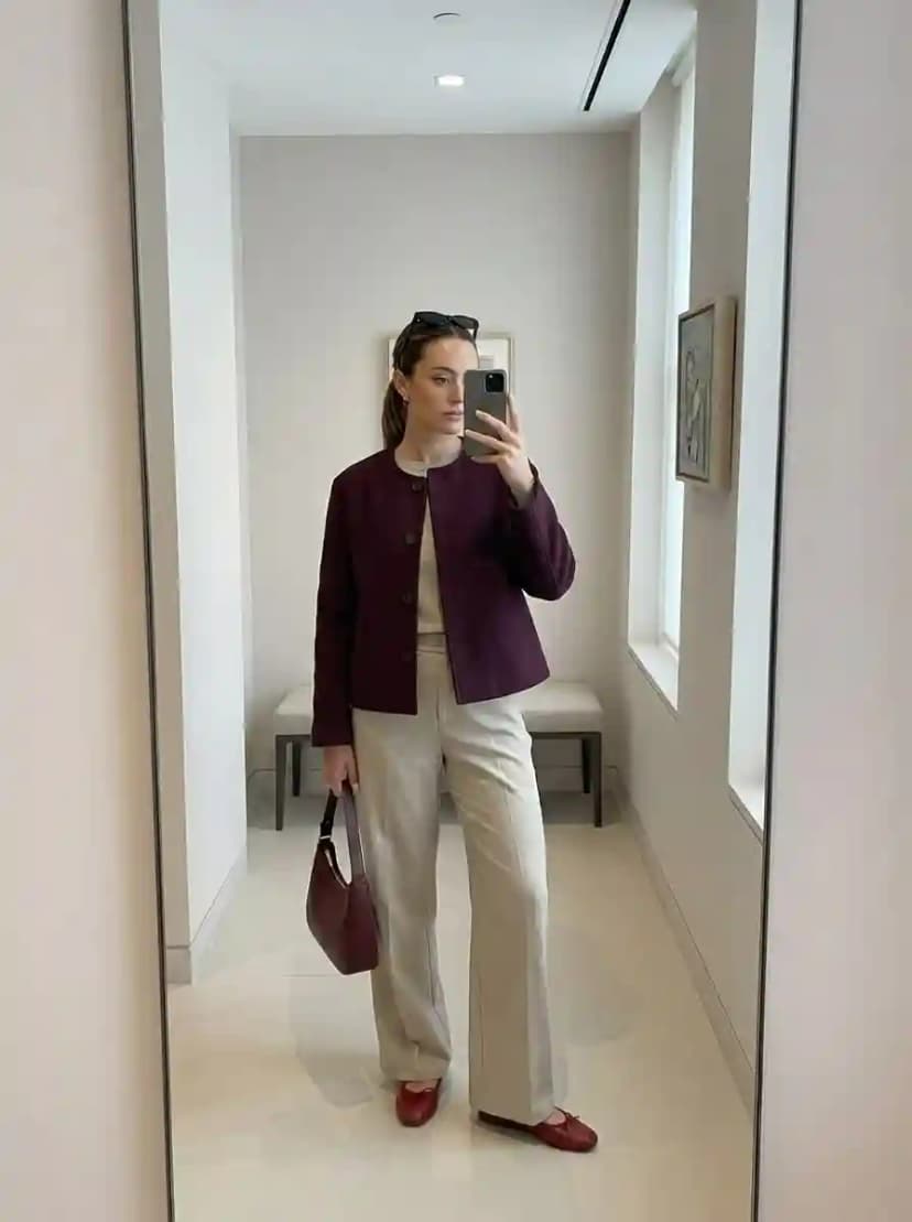 Beige crew-neck top, beige wide-leg trousers, burgundy cropped jacket, and matching burgundy loafers