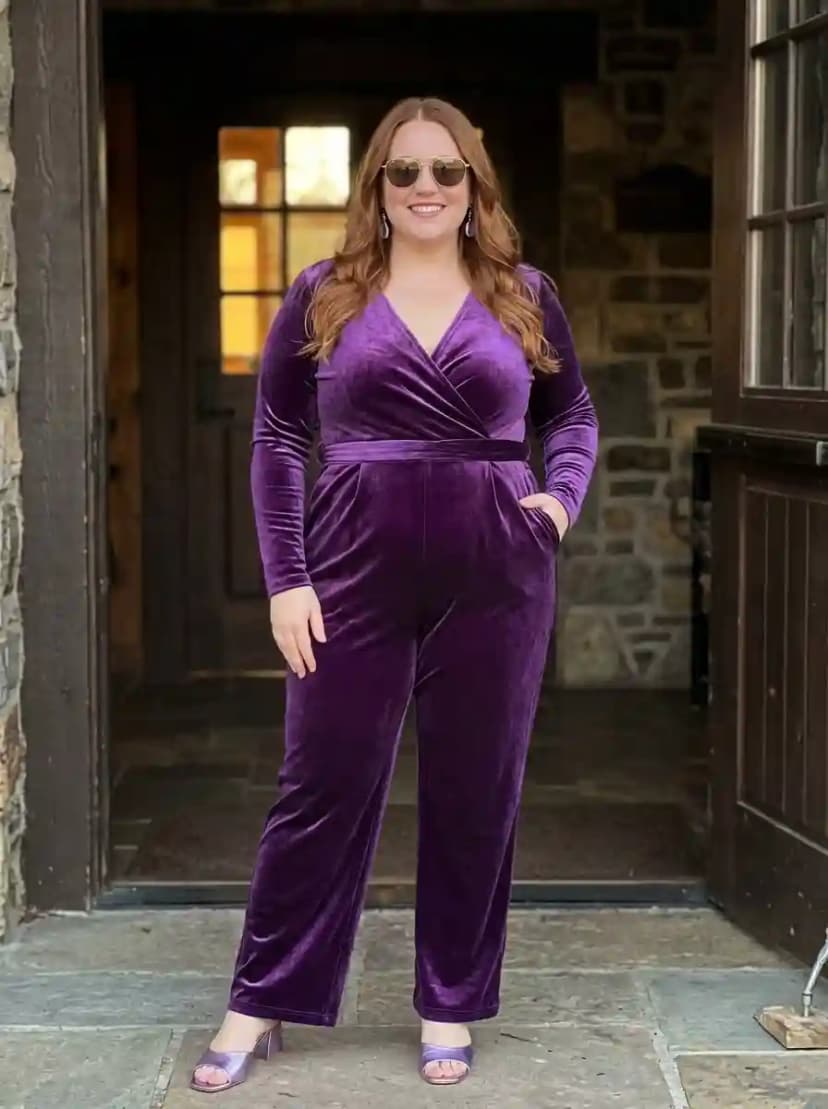 Deep purple velvet wrap-style jumpsuit with V-neckline, long sleeves, and wide-leg trousers