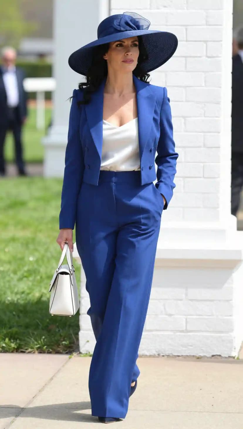 Royal blue pant suit with wide-brim hat and white structured bag