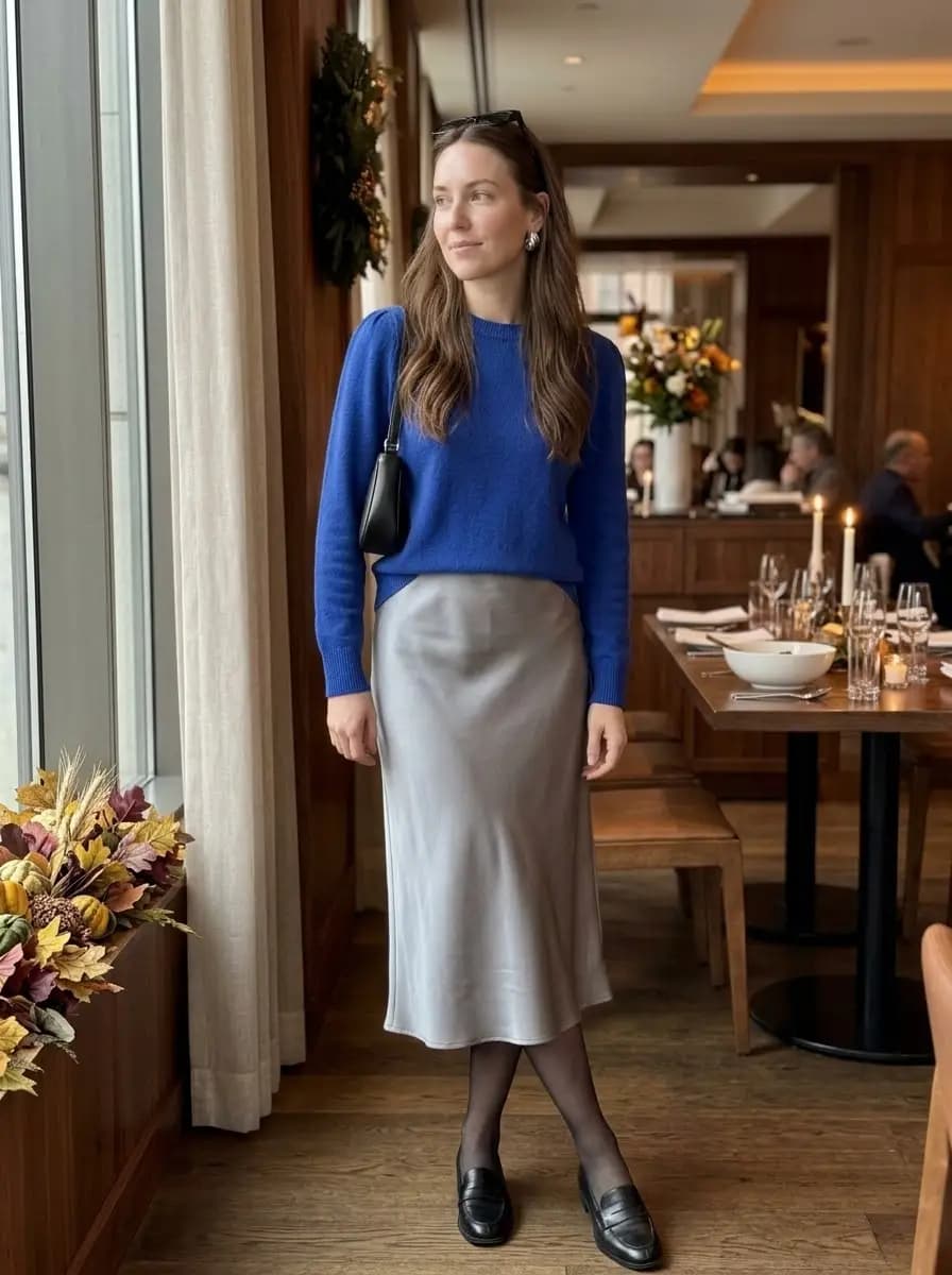 Royal blue knit sweater with silver satin midi skirt and black loafers